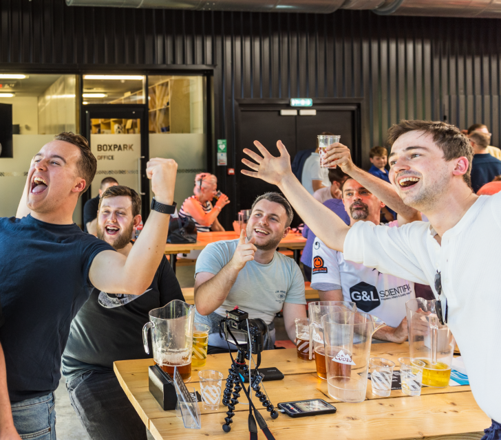 Bunch of guys cheering at the football on the telly